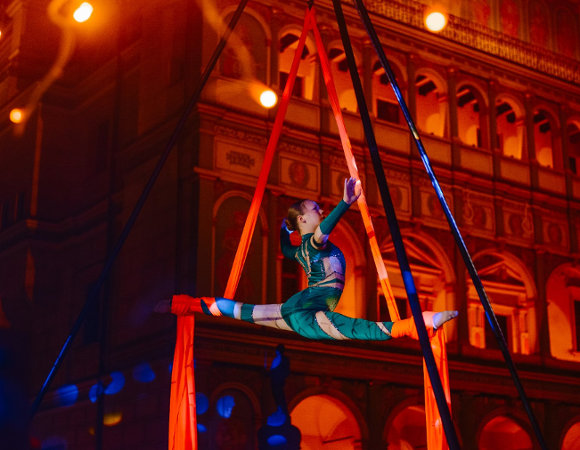 akrobatka wykonuje układ na szarfie na tle ratusza